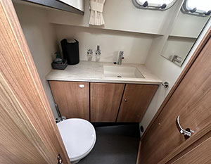 Linssen GS 35 AC Mi Tiempo Nasszelle Bugkabine. Blick dutrch Tür in Nasszelle; links unten Toilette, Blick nach vorne Waschtisch – Becken rechts, darüber unterer Rand des Bullauges zu sehen