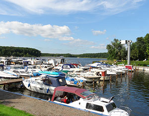 Mirow – Anleger mit Booten. Blick von Land aus über die Boote zum See