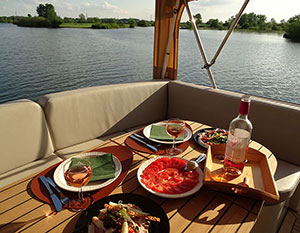 Tempranillo Achterdeck mit Sitzbank und gedecktem Tisch in der Abendsonne, Blick auf das Wasser